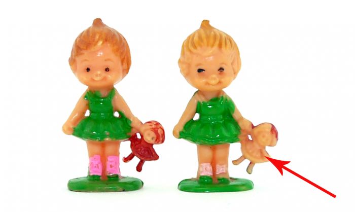 Mädchen mit Puppe in der Hand, wo die Vorderseite der Puppe nicht rot bemalt ist (fehlende Bemalung)
