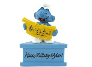 Singender Schlumpf auf blauem Sockel - Happy Birthday to You -